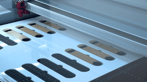 Bottle openers that are being branded with a logo via a gantry engraving machine.